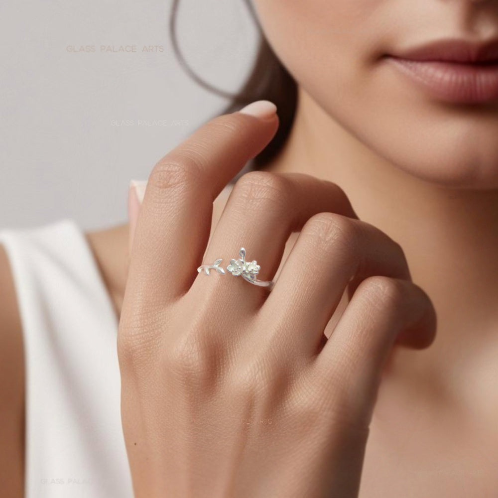 A silver floral ring with an adjustable band featuring a blooming rose design, worn on a person's finger.