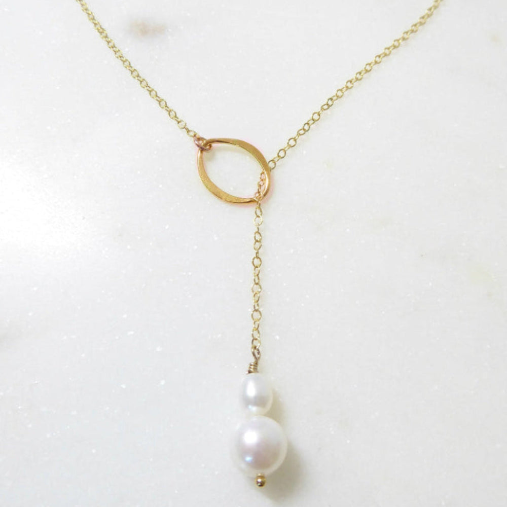 Gold necklace with a single pearl on a white background