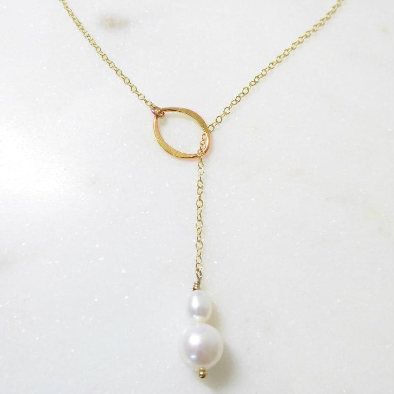 Gold necklace with a single pearl on a white background