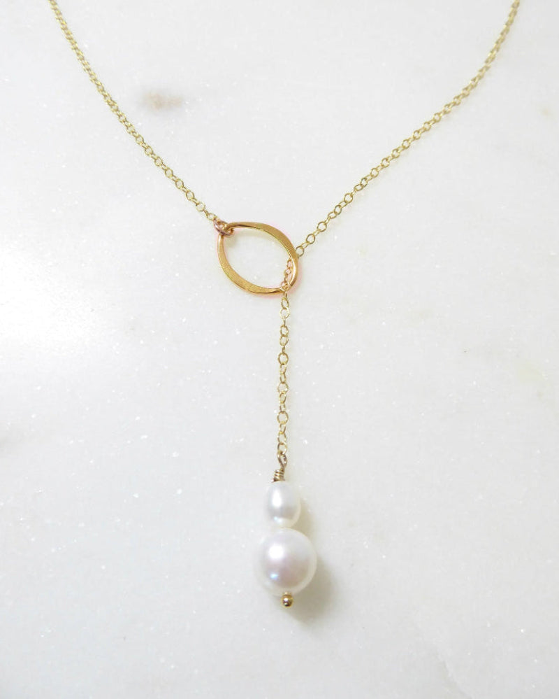 Gold necklace with a single pearl on a white background