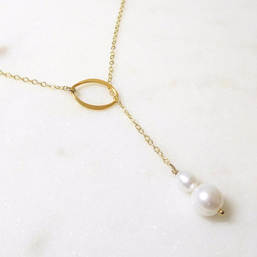 Gold necklace with pearl pendants on a white background