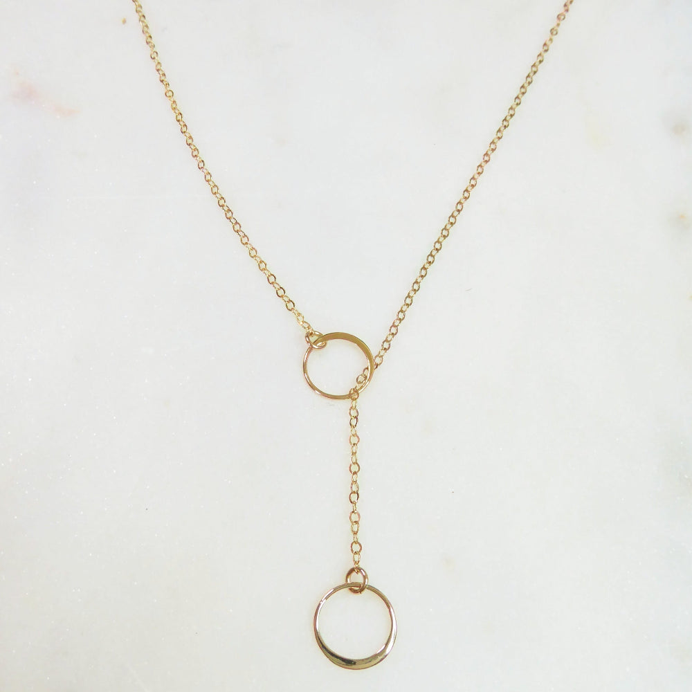 Gold necklace with a lariat design on a light background