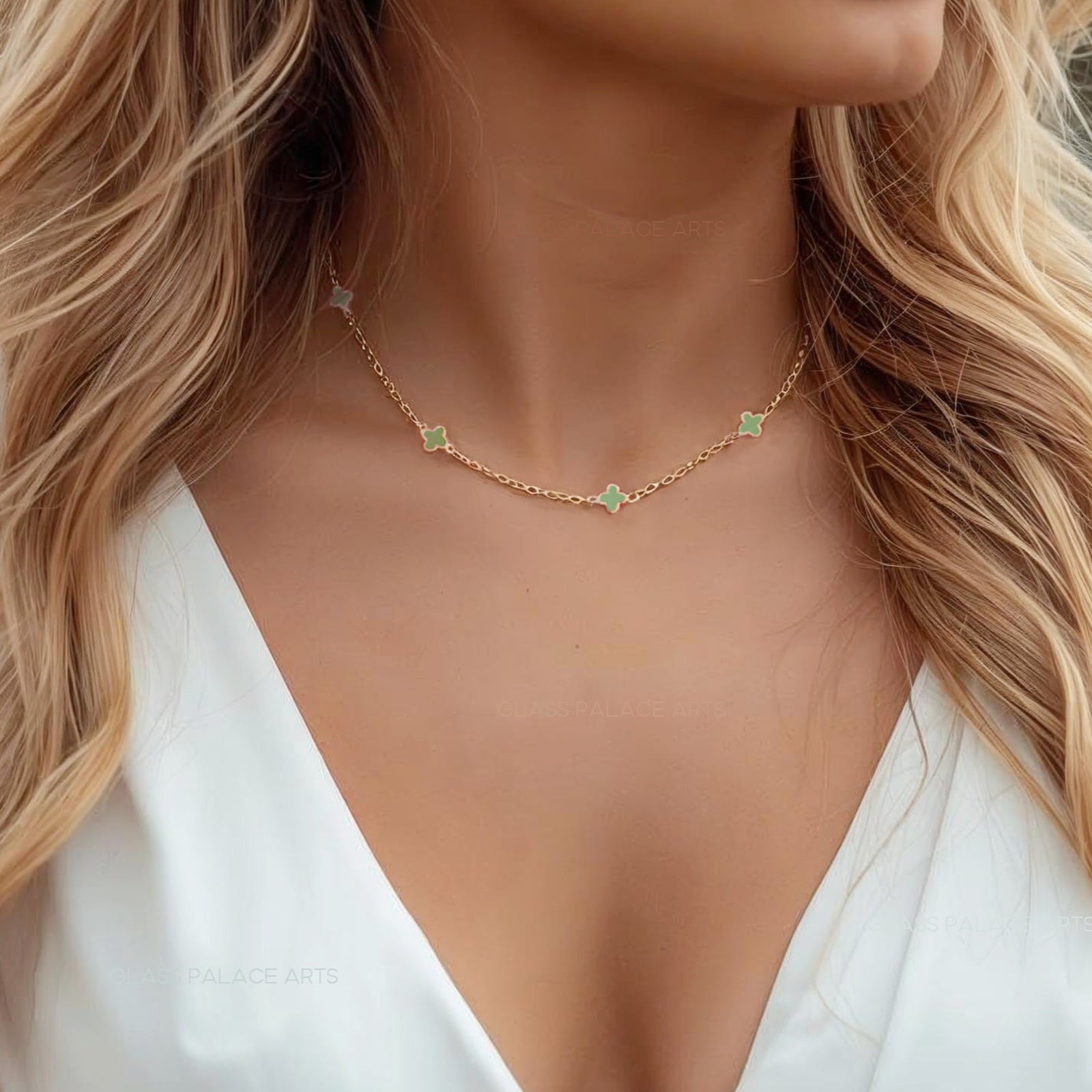 Woman wearing a white top and gold necklace with a blurred natural background