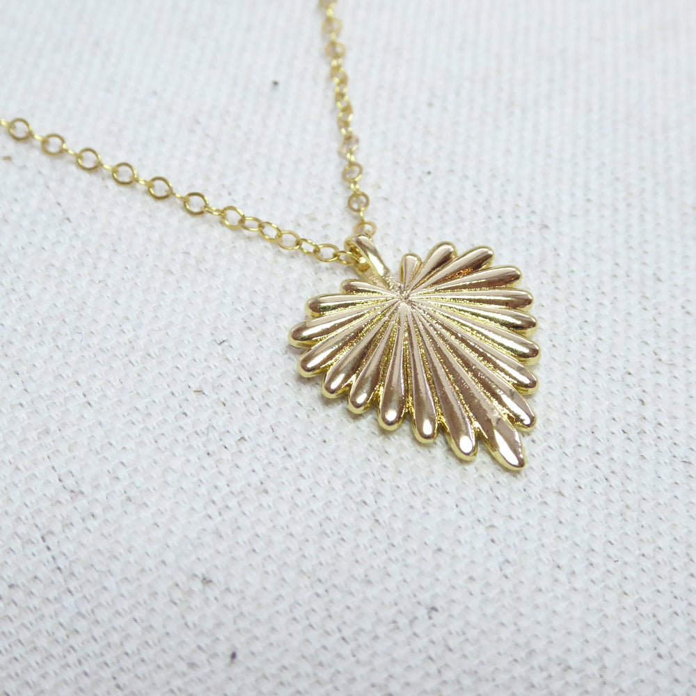 Gold necklace with a shell pendant on a white fabric background
