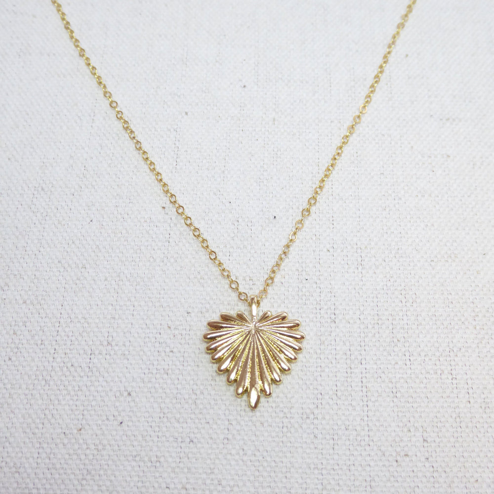 Gold necklace with a heart-shaped pendant on a light gray background