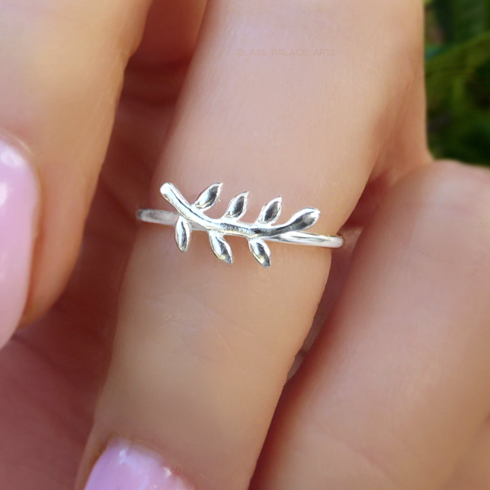 Silver leaf ring on a finger with a blurred natural background