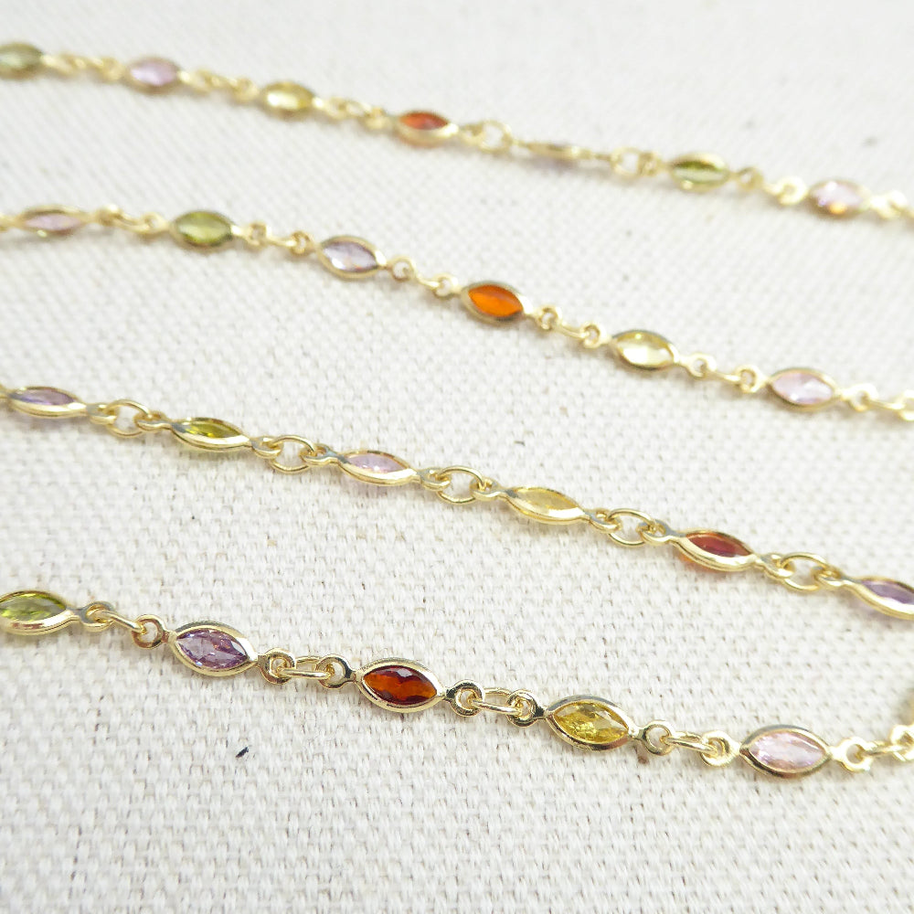Gold chain with embedded multicolored gemstones on a white background
