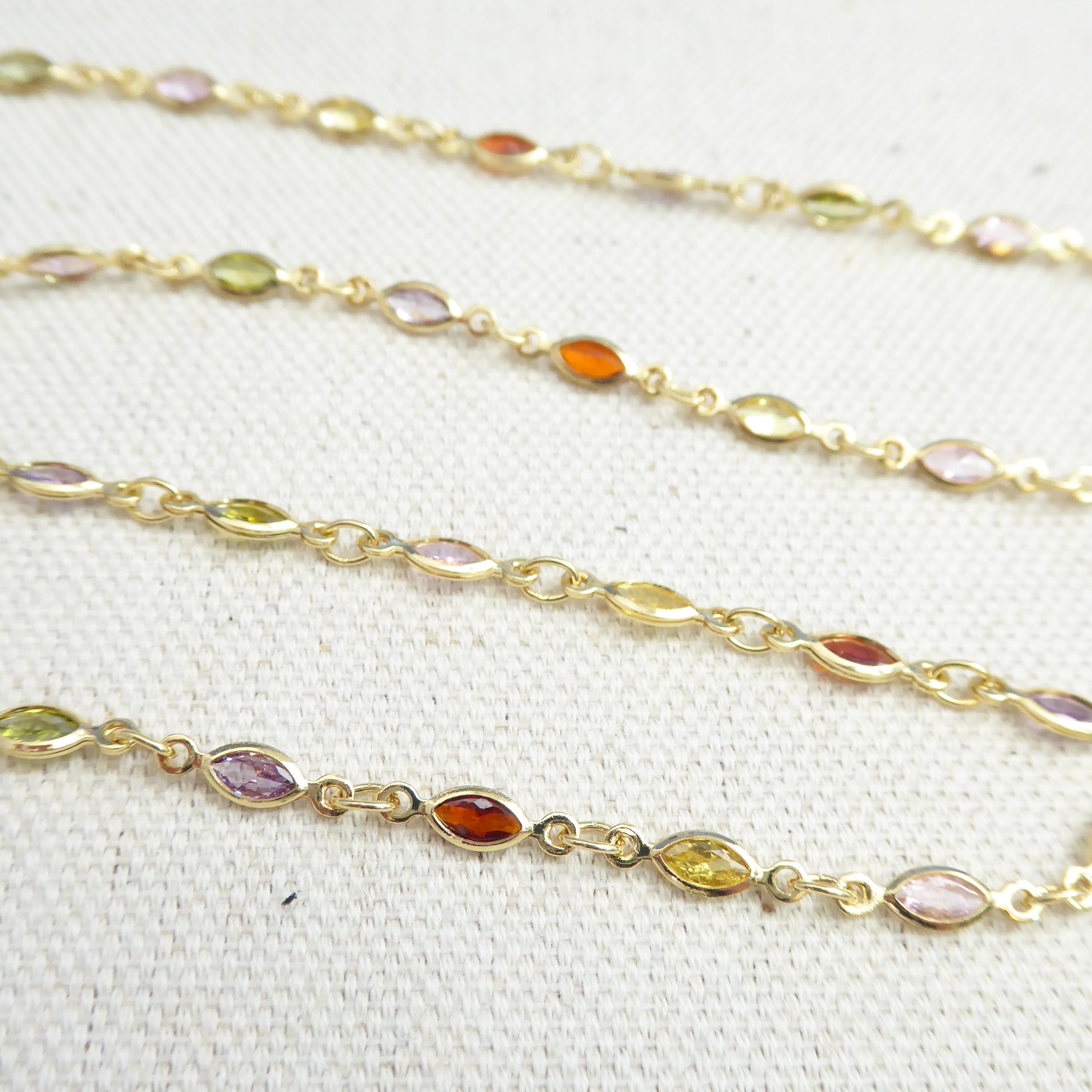 Gold chain with embedded multicolored gemstones on a white background