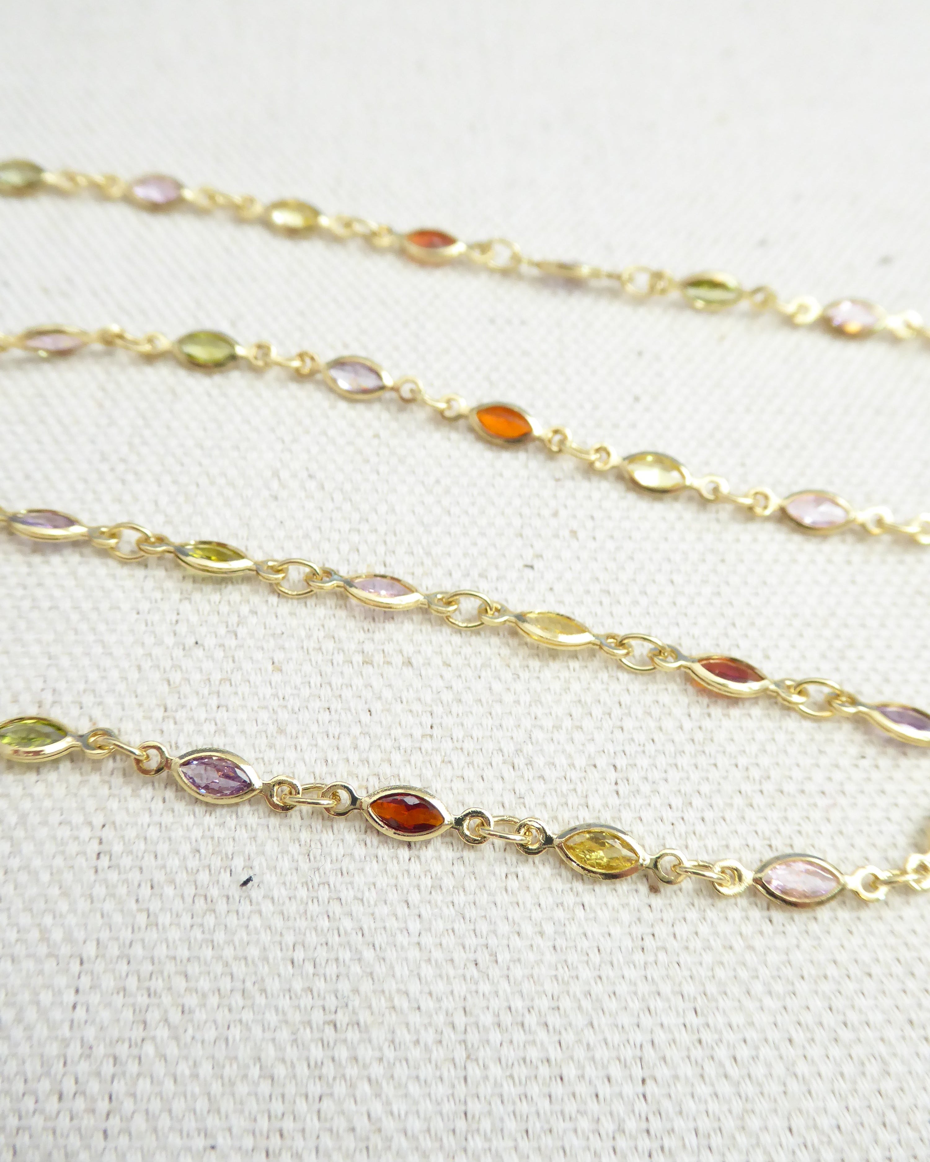 Gold chain with embedded multicolored gemstones on a white background