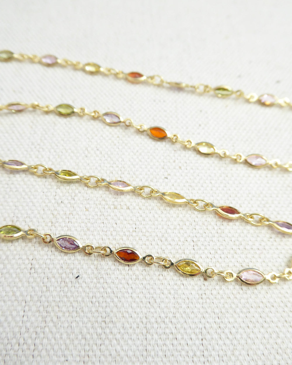 Gold chain with embedded multicolored gemstones on a white background