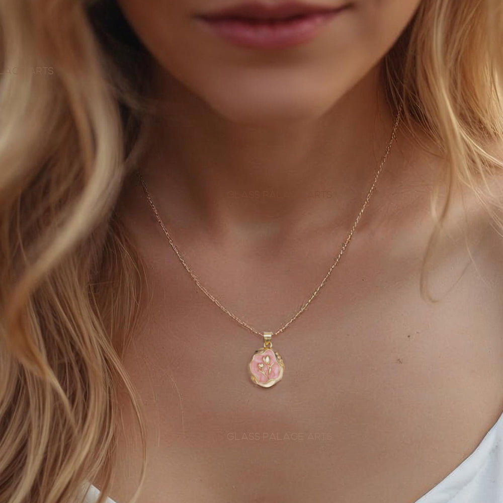 Woman wearing a gold necklace with a small pendant, blurred background