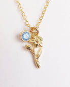 Gold necklace with a blue gemstone and floral design on a white background