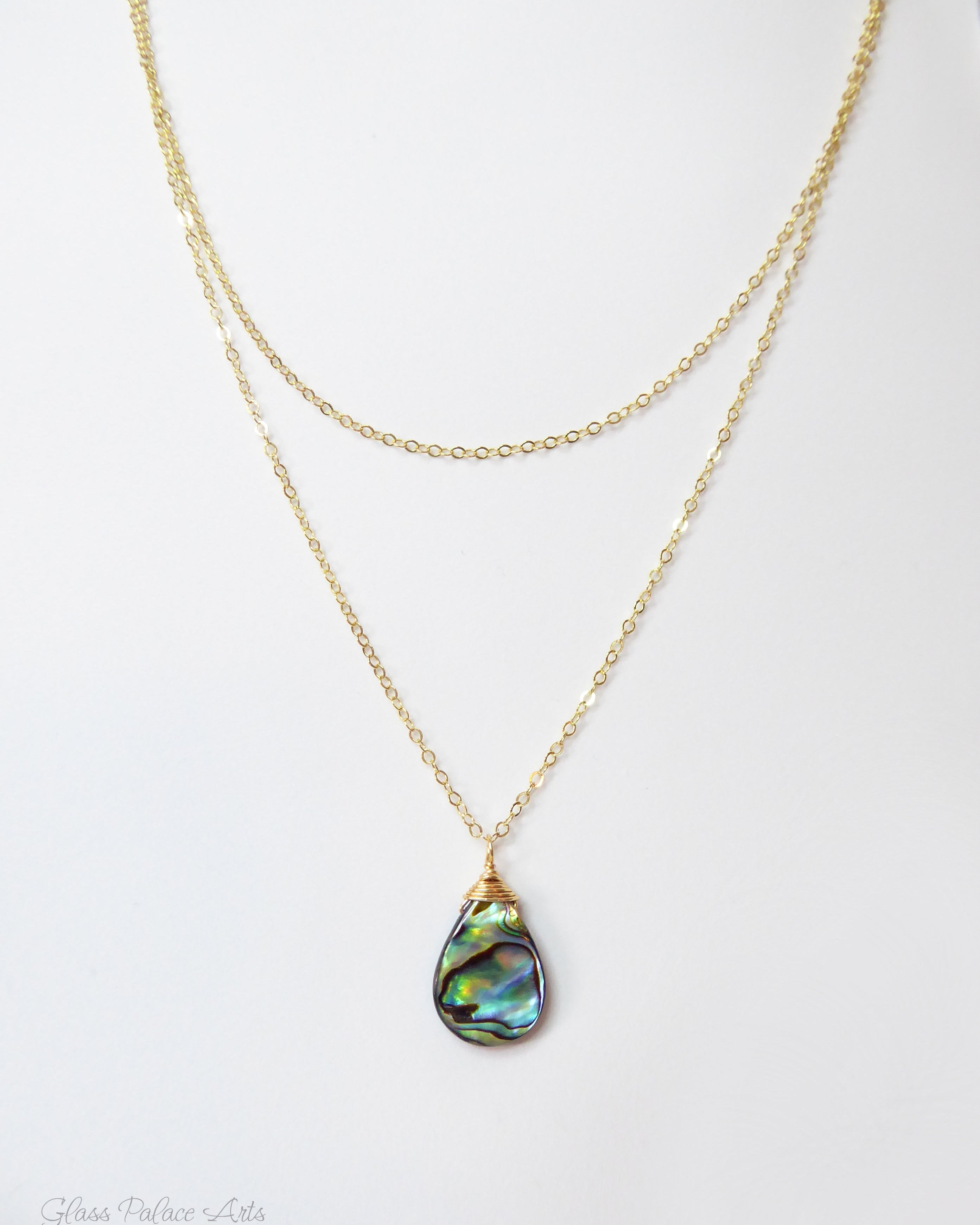 Gold necklace with a teardrop-shaped abalone shell pendant on a white background