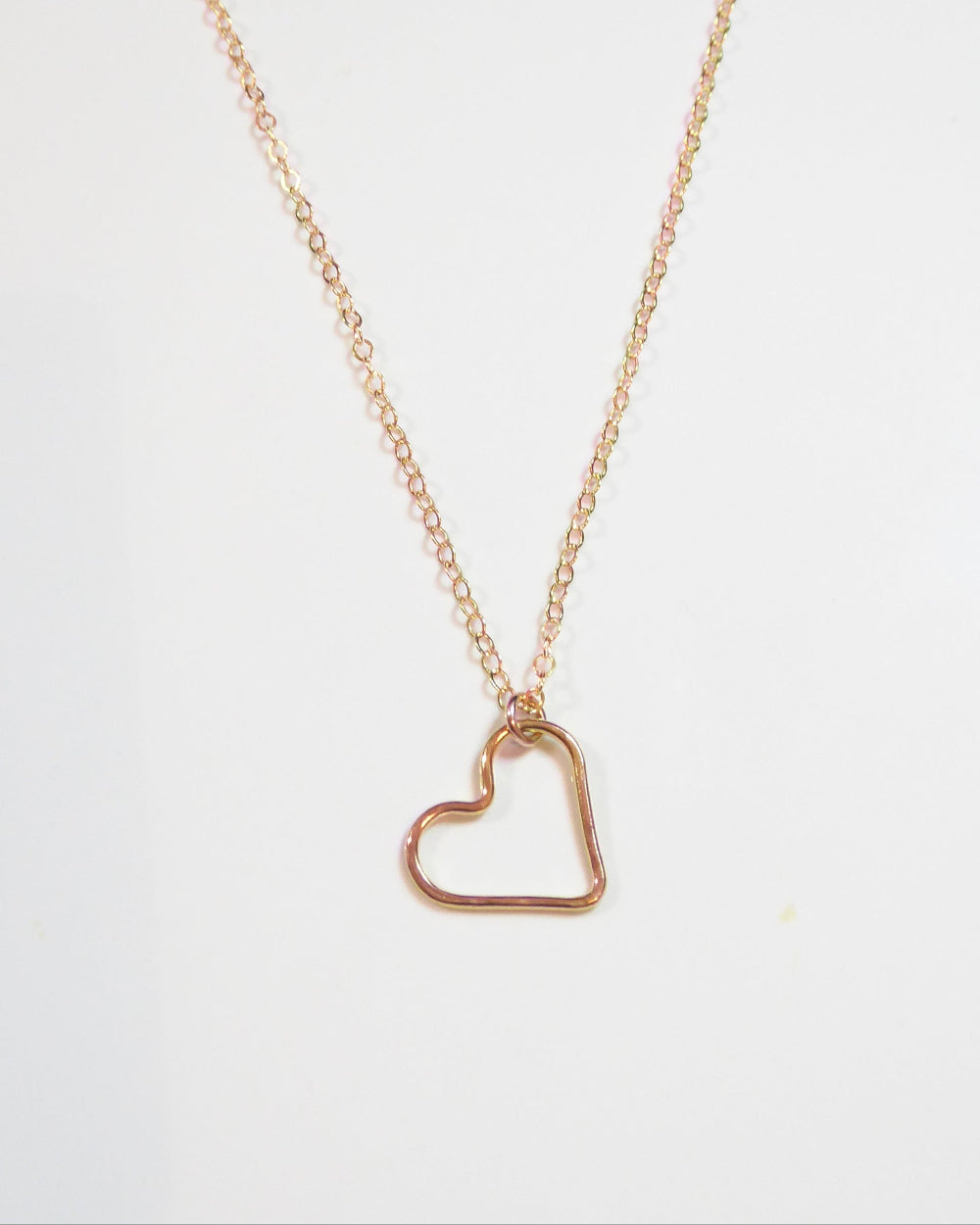 A delicate rose gold chain necklace featuring an open heart-shaped pendant, displayed against a clean white background with a subtle watermark at the top.