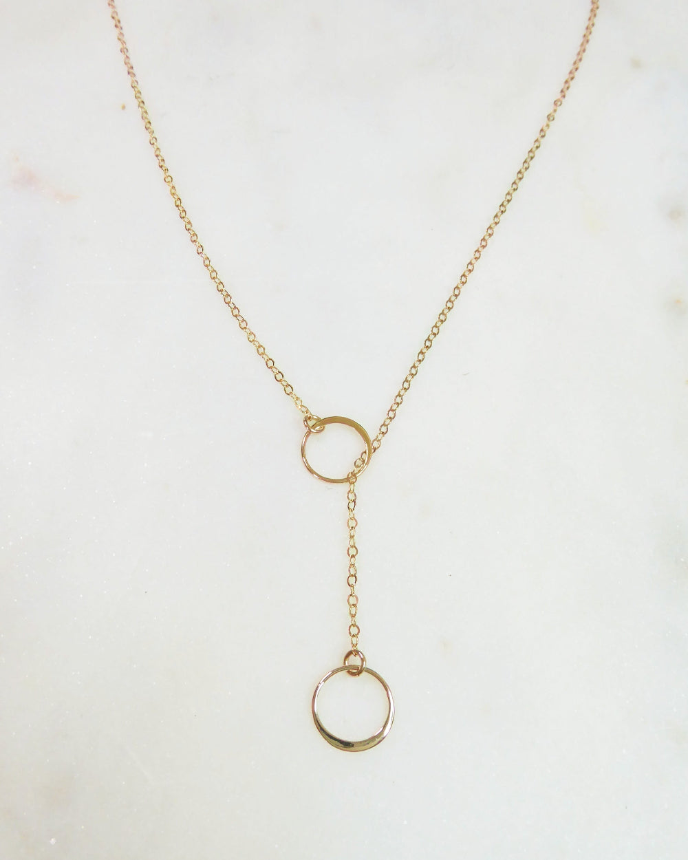 Gold necklace with a lariat design on a light background