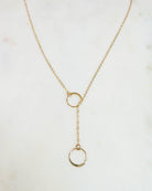 Gold necklace with a lariat design on a light background