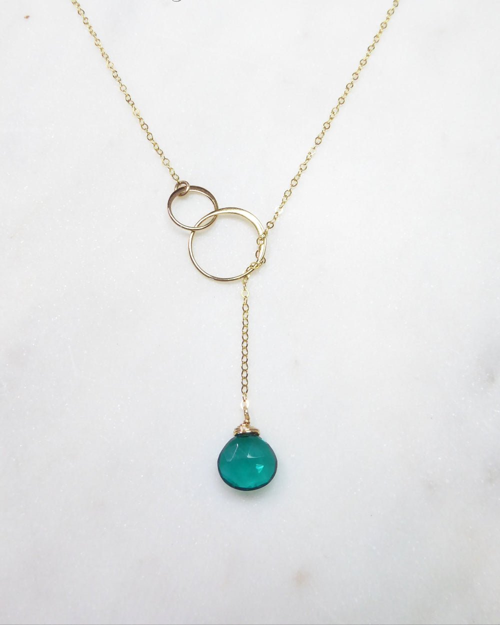 Gold necklace with a green pendant on a white background