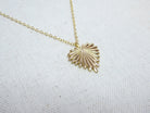 Gold shell pendant necklace on a white fabric background