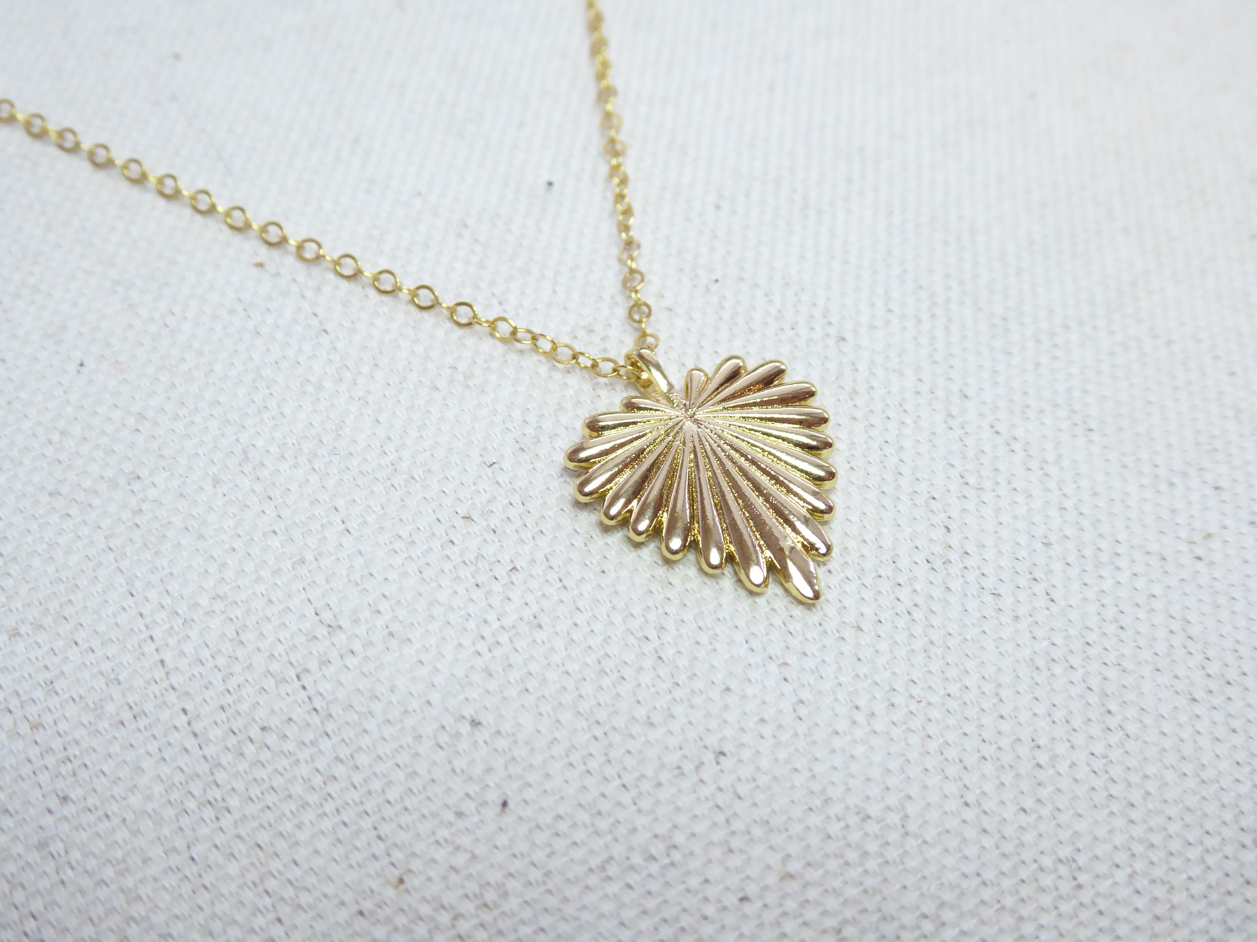 Gold shell pendant necklace on a white fabric background