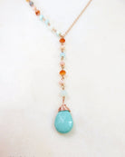 turquoise lariat necklace with small opal beads on the side, on white background